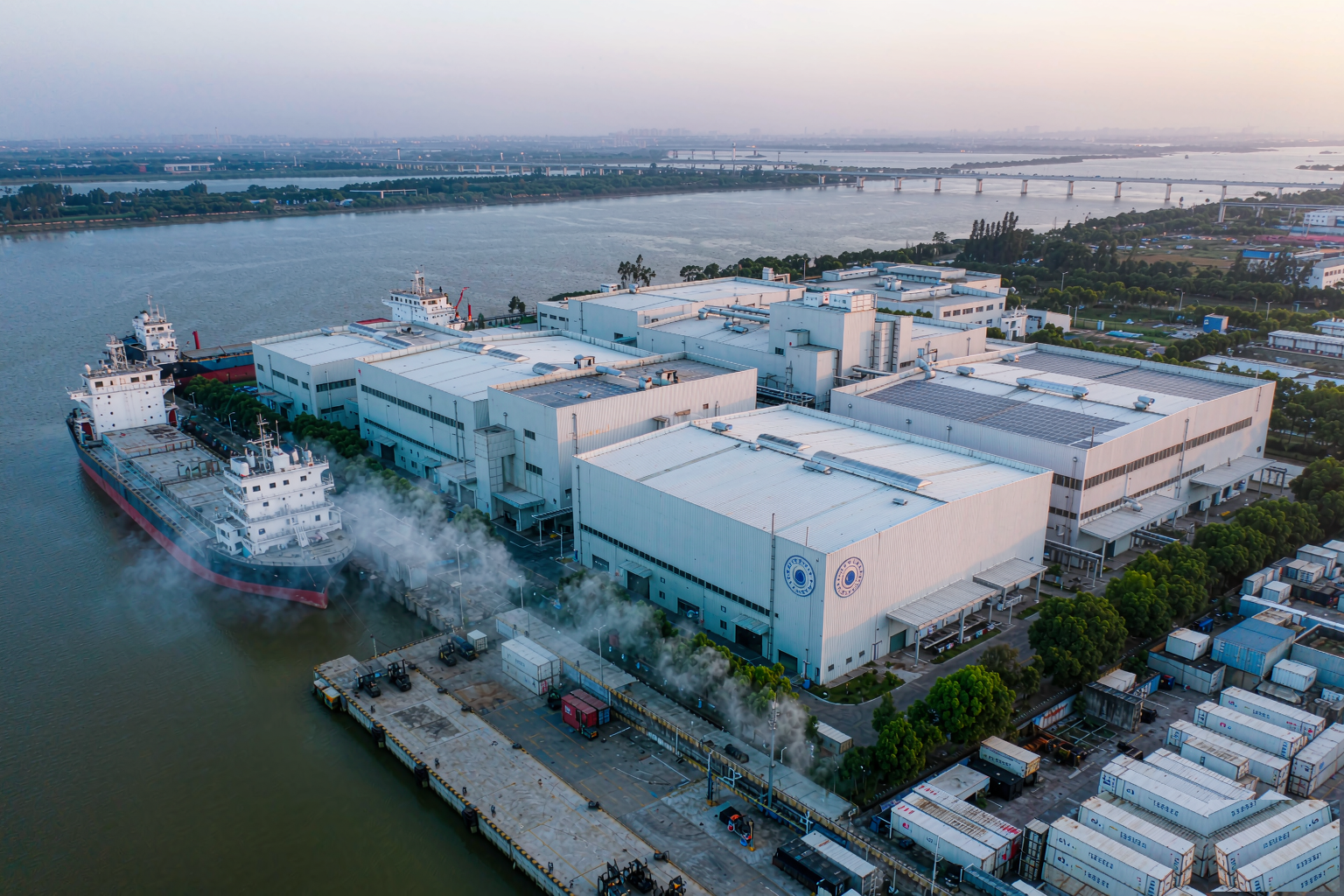 Aerial view of modern whitefish processing plant beside river port with reefer containers